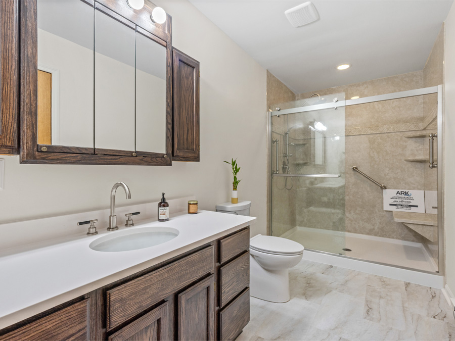 Remodelled bathroom with a white quartz vanity top, oak cabinetry and a glass-door walk-in shower